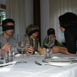 Partecipanti a un corso di lingua seduti a un tavolo con bende sugli occhi.