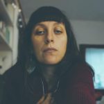 Ritratto di una giovane donna con capelli scuri e orecchini.