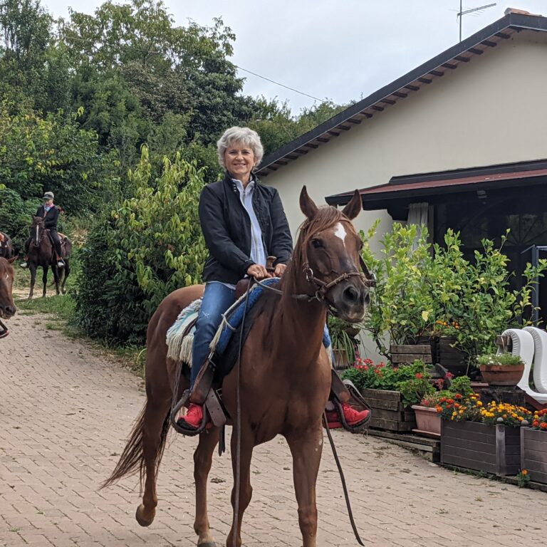 Persone che cavalcano cavalli in un paesaggio verde.