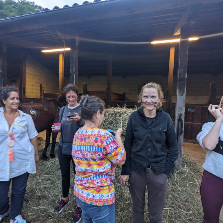 Gruppo di donne con viso dipinto in un ambiente rurale.