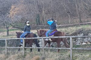 Due persone a cavallo in un'area rurale.